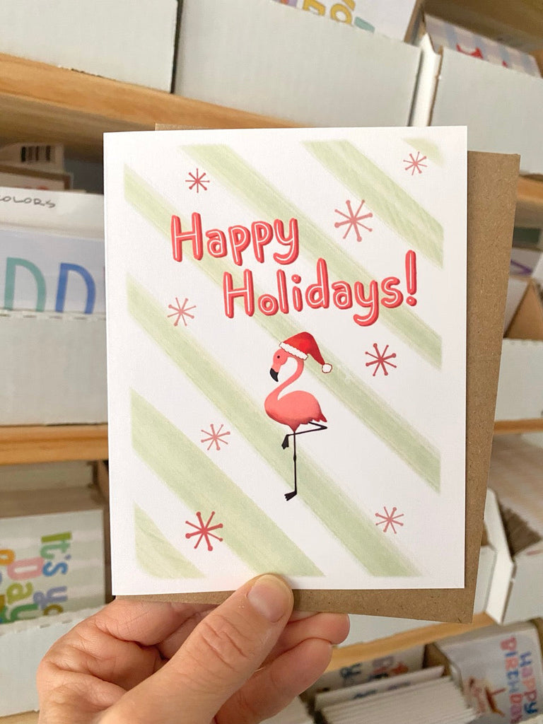 Maggie Moore Happy Holidays card featuring plastic lawn flamingo
